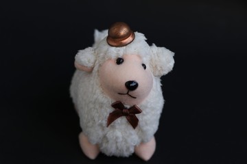 Cute lamb wearing a hat isolated on black.