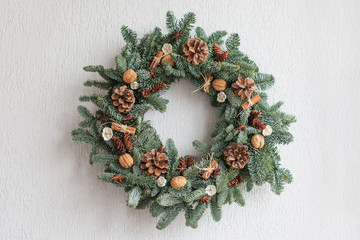 Christmas wreath made of natural fir branches  hanging on a white wall.  Wreath with natural...