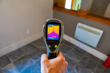 Indoor damp & air quality (IAQ) testing. A close up view on the rear screen of an infrared thermal vision camera, pointing towards the corner of a room with cold tiled floor and warm insulated walls. - obrazy, fototapety, plakaty