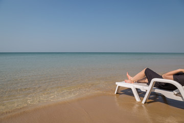 Vacation on tropical beach Woman's legs on the beach bed with clear ocean water