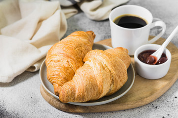 Croissants on a plate with coffee and strawberry jam. pastries for Breakfast