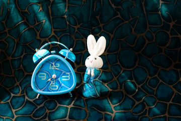 Design blue clock with white fabric rabbit in blue Japanese traditional dress on abstract texture background, time keeper 