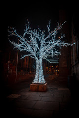 EDINBURGH, SCOTLAND DECEMBER 13, 2018: Amazing sculpture of a tree with a skeleton frame, fulfilled of christmas lights shining and glowing into the dark of the street.