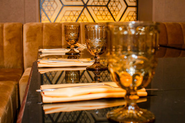 Beautiful graceful glasses. Serving in a restaurant with yellow and gold tones in the interior