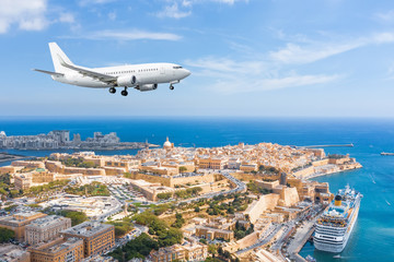 Passenger plane approach landing at Malta Valletta great bay with a cruise liner ship.