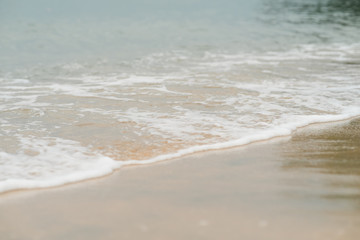 Soft waves with foam of ocean on the sandy beach background