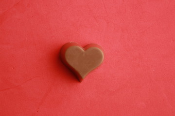 Chocolate bonbon with heart shape in color background