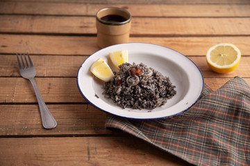 Plate of black rice with squid and prawns or Valencian black paella