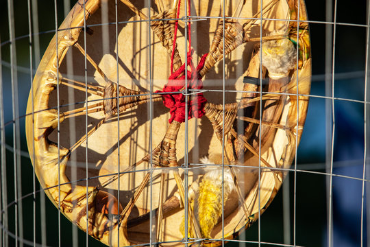 Sacred drums during spiritual singing. A closeup view on the rear of a traditionally crafted native drum with rawhide membrane stretched, tied & knotted, hanging outdoors during a spiritual gathering