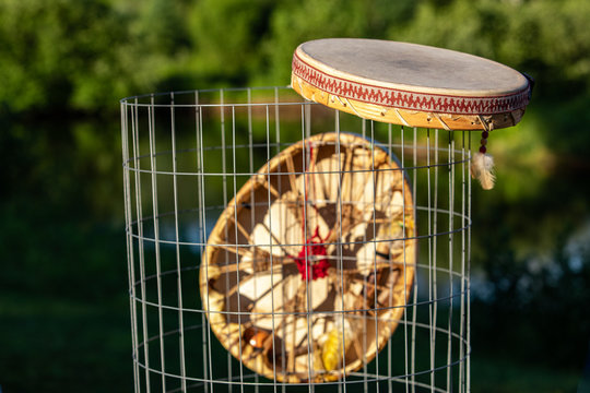 Sacred drums during spiritual singing. Two Native American hand drums are seen closeup, hanging from a mesh waste bin in a park during summer for a cultural music gathering.