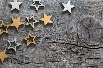 Wooden stars painted in gold and silver color on old wood board  with copy space for text. Wooden  background with Christmas decorations in a rustic style.