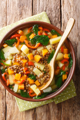 Italian healthy soup with lentils and spinach close-up in a bowl. Vertical top view