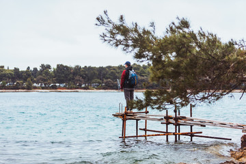 young man standing on pier looking at storm sea