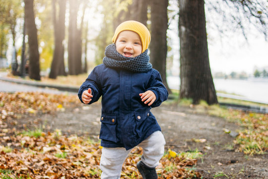 Cute happy baby boy in fashionable casual clothes in autumn nature park