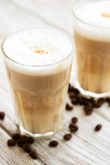Two glasses of latte coffee and coffee beans