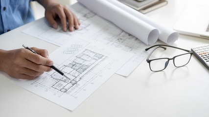 Architect or Engineer working in office with engineering tools, blueprint and building model....