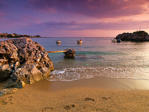 Beautiful sandy beach with rocks in the sea, small bridge and  boats at dusk time, Stoupa, Peloponnese, Greece.