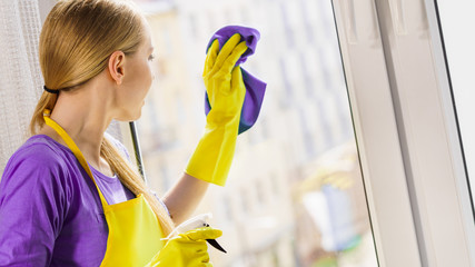 Girl cleaning window at home