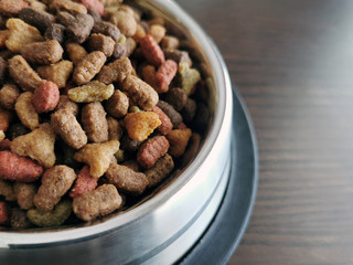 Dry cat food in a bowl on wood background. Copy space is on the right side of the bowl. 