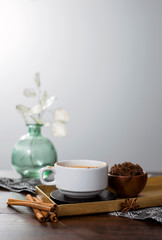 chai tea spices, chai tea latte with ginger root, cinnamon, cardamom pods, star anise, whole nutmeg, peppercorns, whole cloves on golden tray, grey cloth napkin on wooden table, copyspace, copy space