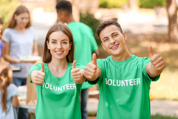 Young volunteers showing thumb-up gesture outdoors