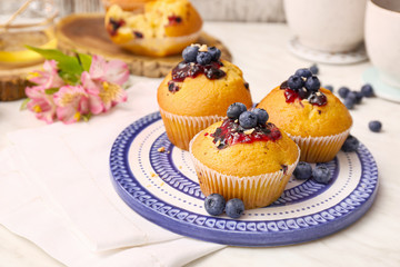 Plate with blueberry muffins on white table