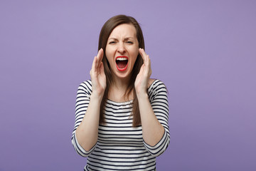 Crazy young brunette woman in casual striped clothes posing isolated on violet purple background studio portrait. People lifestyle concept. Mock up copy space. Screaming with hands gesture near mouth.