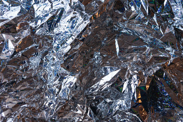 Creative photo background of silver crumpled foil with highlights and shadows