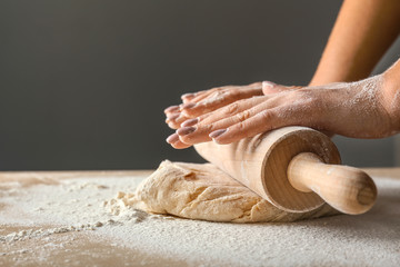 Woman rolling out dough in kitchen, closeup