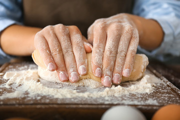 Woman kneading flour in kitchen, closeup