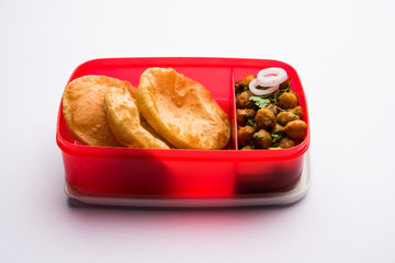 Punjabi Chole / Choley masala with puri or poori in lunch box or tiffin, selective focus