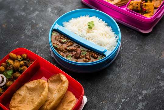 Group of North Indian Food in Tiffin / Lunch Box includes Rajma / Razma Chawal, paneer Butter Masala Roti / Paratha and choley puri / Poori / Bhature, selective focus