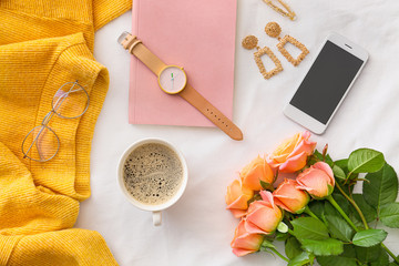 Rose flowers with mobile phone, cup of coffee and female accessories on white background