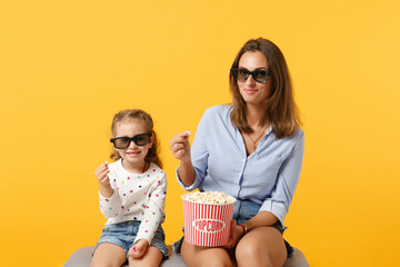 Obraz premium Woman have fun with child baby girl 4-5 years old. Mommy little kid daughter in 3d glasses watch movie film isolated on yellow background studio portrait. Day love family parenthood childhood concept.