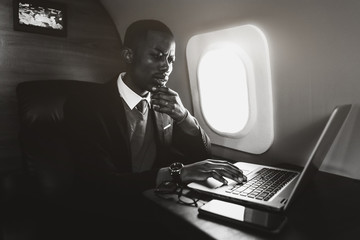 Attractive and successful African American businessman with glasses working on a laptop while...