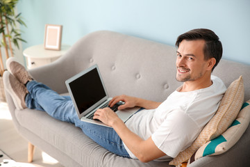 Handsome man with laptop resting at home