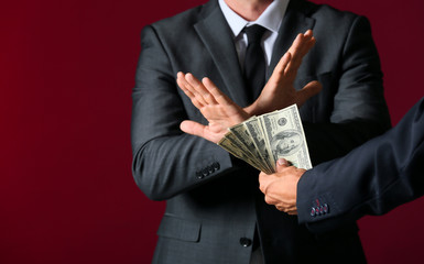 Businessman refusing to take bribe against color background
