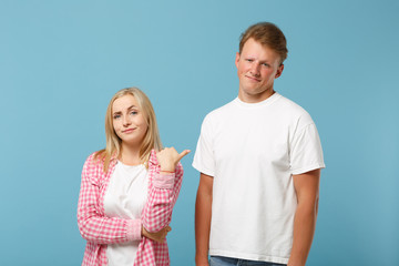 Young fun couple two friends guy girl in white pink empty blank design t-shirts posing isolated on pastel blue background studio portrait. People lifestyle concept. Mock up copy space. Discuss issue.