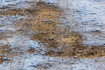 A frozen puddle covered with snow in the rays of the dawn of the sun in winter