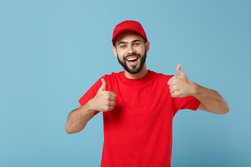 Delivery man in red uniform workwear isolated on blue wall background, studio portrait. Professional male employee in cap t-shirt print working as courier dealer. Service concept. Mock up copy space.