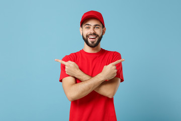 Delivery man in red uniform workwear isolated on blue wall background, studio portrait. Professional male employee in cap t-shirt print working as courier dealer. Service concept. Mock up copy space.