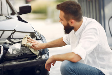 Man in a white shirt. Worker wipes a car. Male holding a rag in his hand