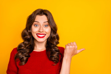 Photo of cheerful curly wavy charming cute girlfriend pointing at something with her finger thumb showing direction isolated over yellow vivid color background - obrazy, fototapety, plakaty