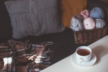Woolen yarn and knitting needles in basket and tea
