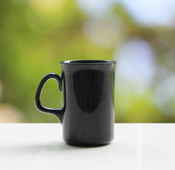 A black coffee mug on a white table On a natural background