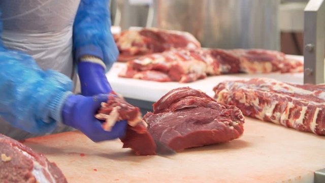 Butcher cutting beef by the conveyor belt