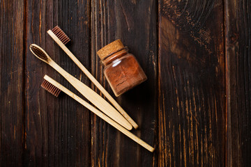Close up of three bamboo toothbrushes and tooth powder