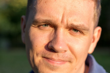 Man with a scornful disdainful disrespectful look. Portrait of a young guy on nature background, feelings and people reaction.