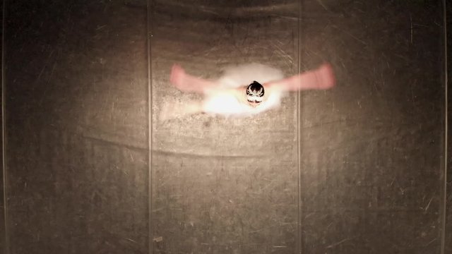 Top view of dancing ballerina in white tutu on a black background. Ballerina spinning performing fouette. Taken by drone, looking down