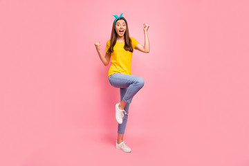 Full body photo of cheerful girl raising fists screaming wow omg yeah wearing yellow t-shirt isolated over pink background